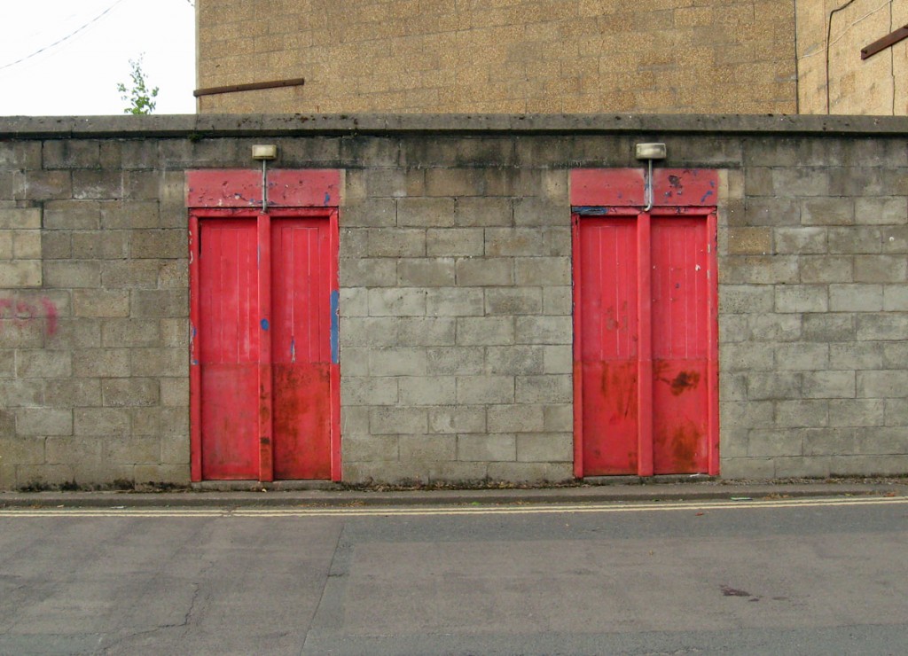 Red painted turnstile gates in grey block wall