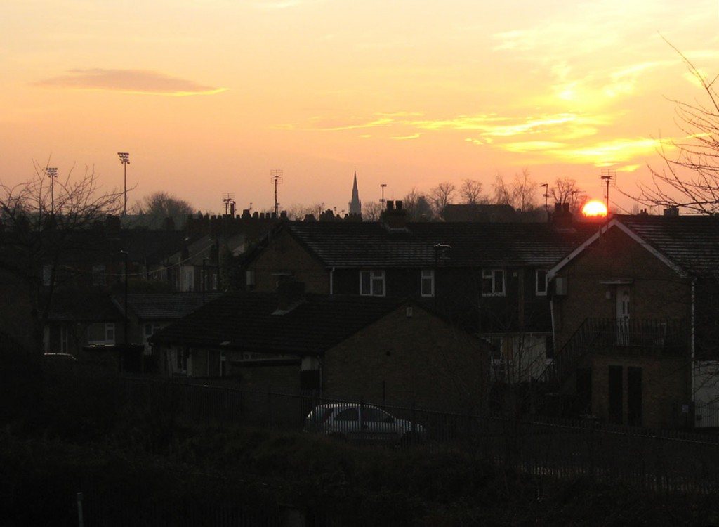 Sunset, with floodlights and church spire on horizon