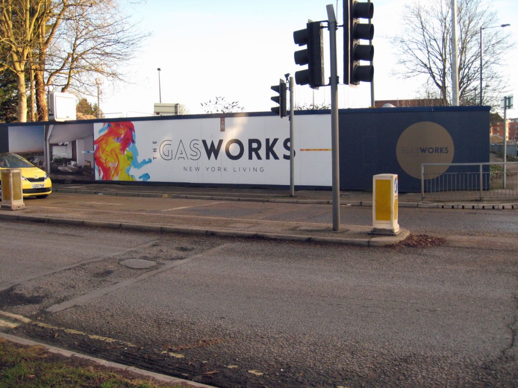 Ads on building site hoardings, by a road