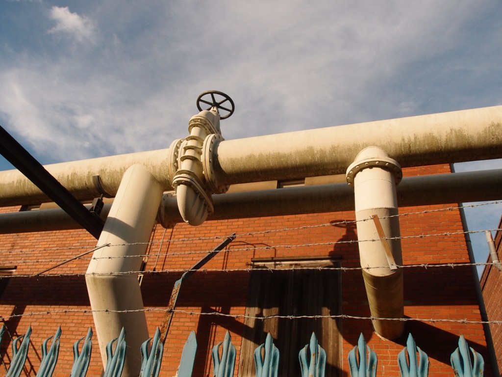 Large pipes with red brick behind, blue railings in front
