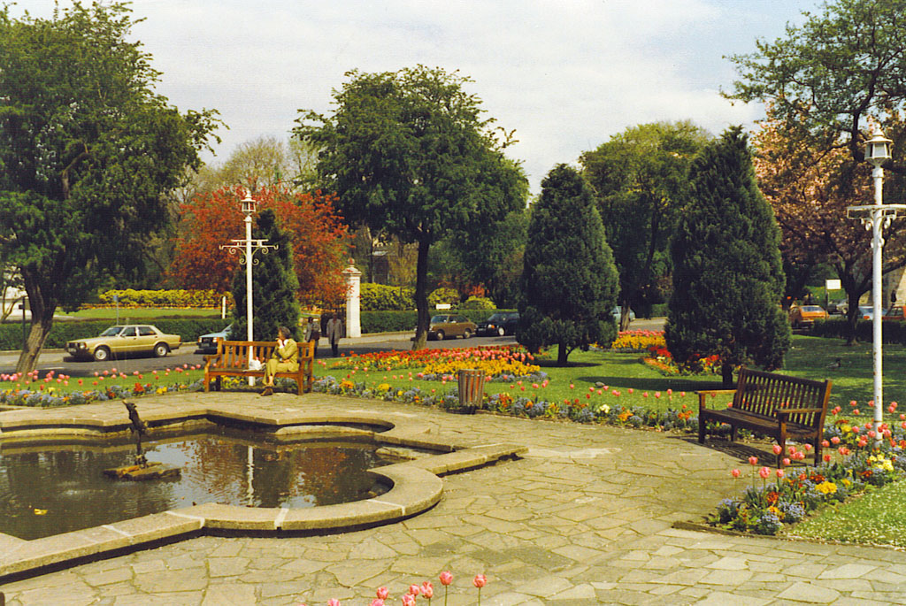 Park with bright flowers and pond, in sunshine