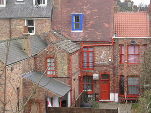 The backs of buildings on Gillygate, with brightly painted window frames, viewed from the city walls.