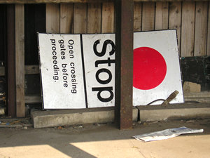 Abandoned sign reads: 'Stop. Open crossing gates before proceeding'